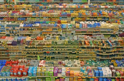 Image looking down on a large supermarket type store - looking across the tops of multiple aisles, showing huge amounts of multi-coloured products with printed labels and packaging on.